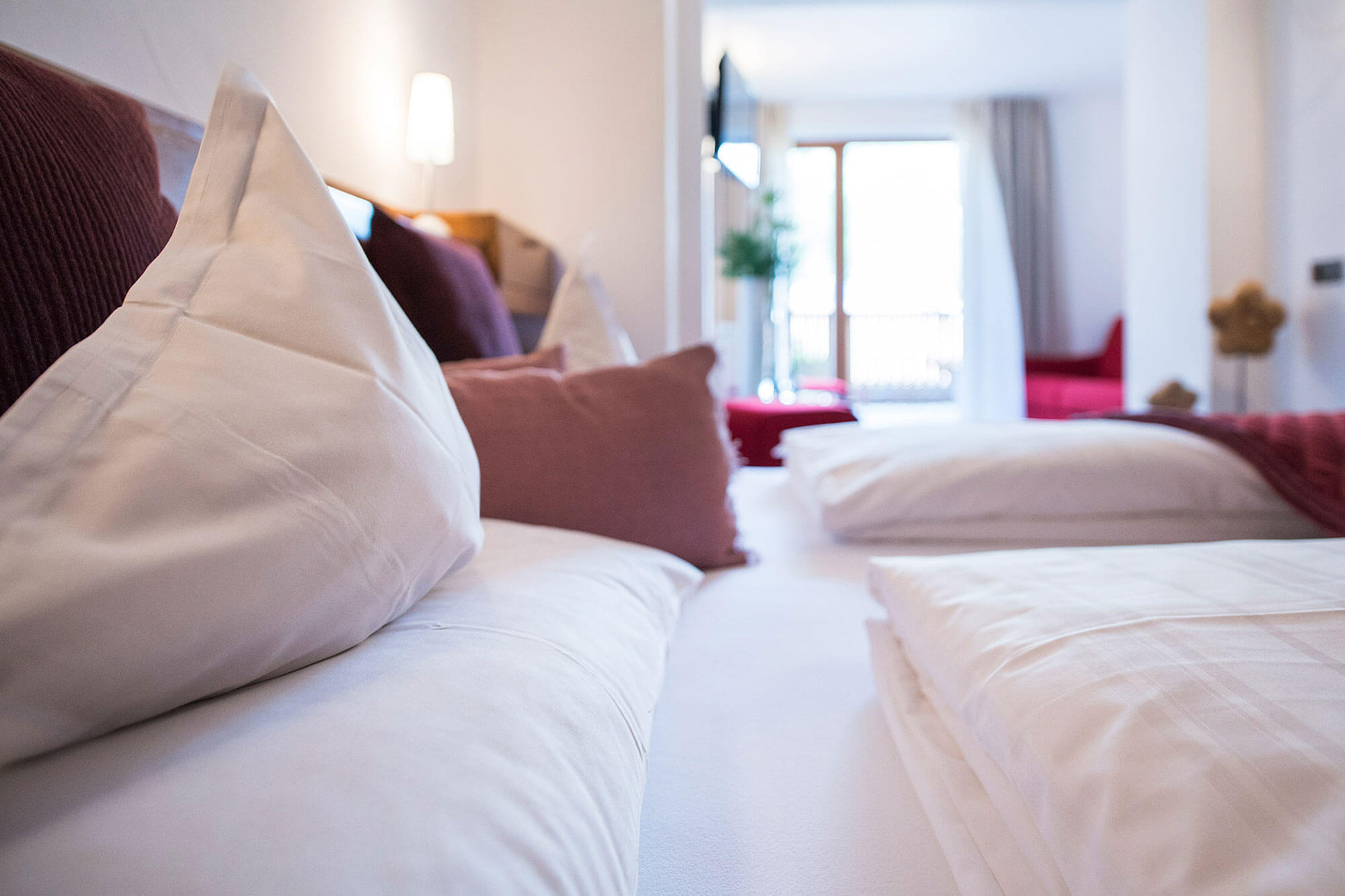 Hotelzimmer mit Doppelbett mit roten und weißen Kissen - Hotel Mühlwald