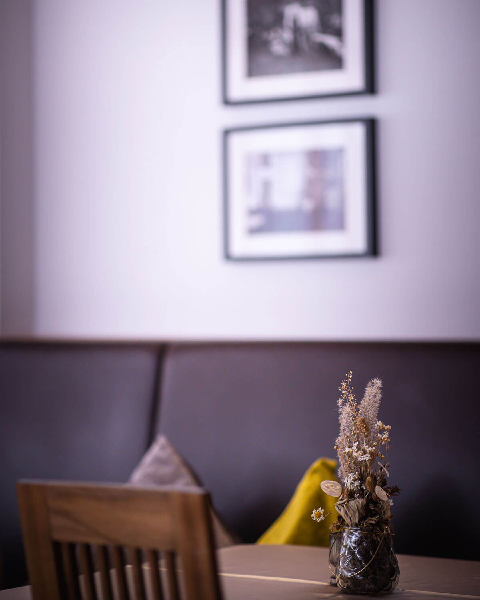 Tisch im Speisesaal mit Bilder an der Wand im Hintergrund - Hotel Mühlwald