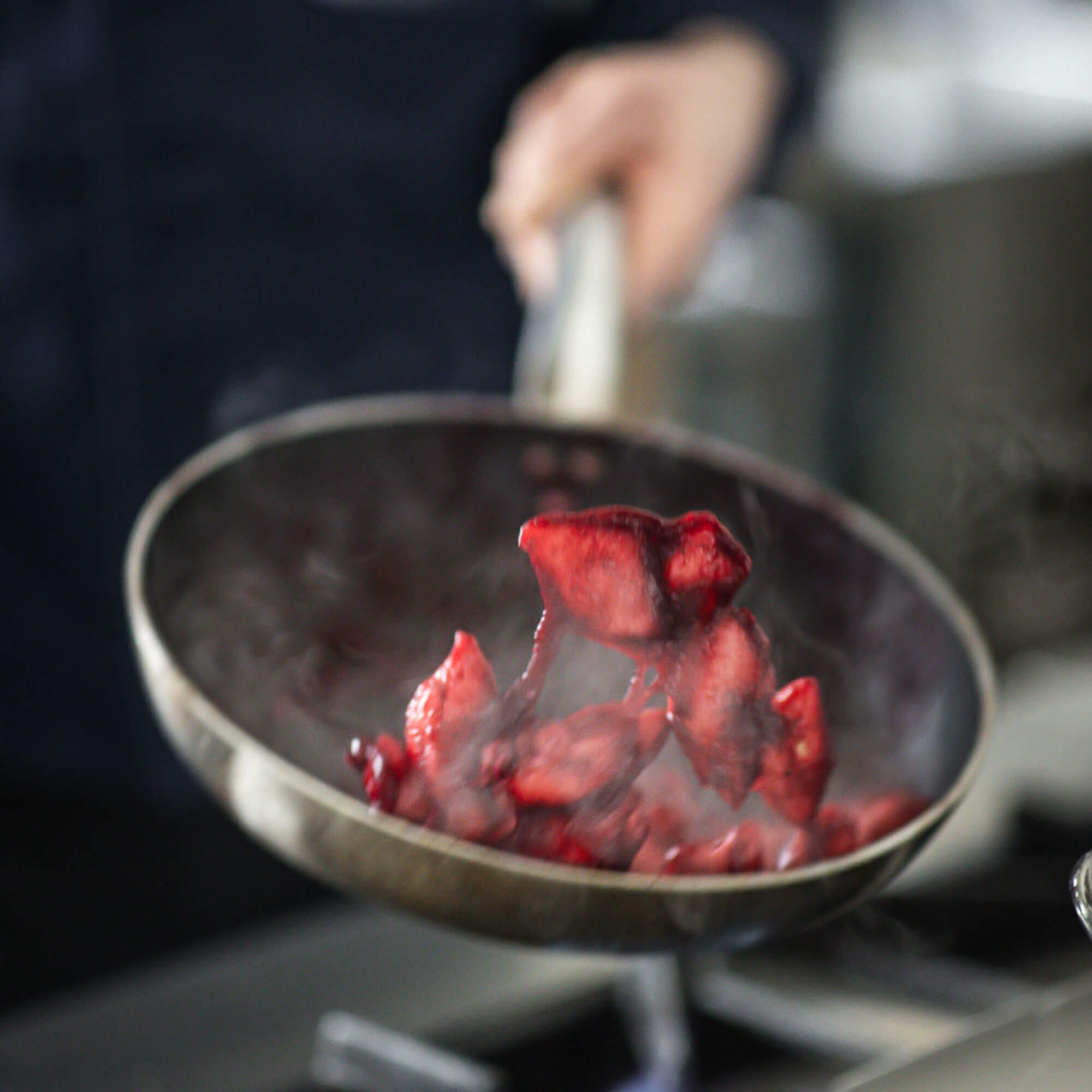 Der Koch schwenkt das Essen in der Pfanne - Hotel Mühlwald